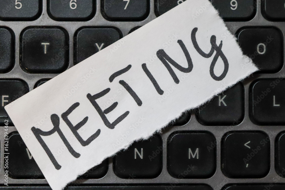 Poster a note reading meeting placed on a black computer keyboard, symbolizing organization and productivit