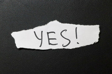 A torn piece of paper on a black background with the word YES! written in bold letters. This image conveys positivity and affirmation suitable for various motivational contexts.