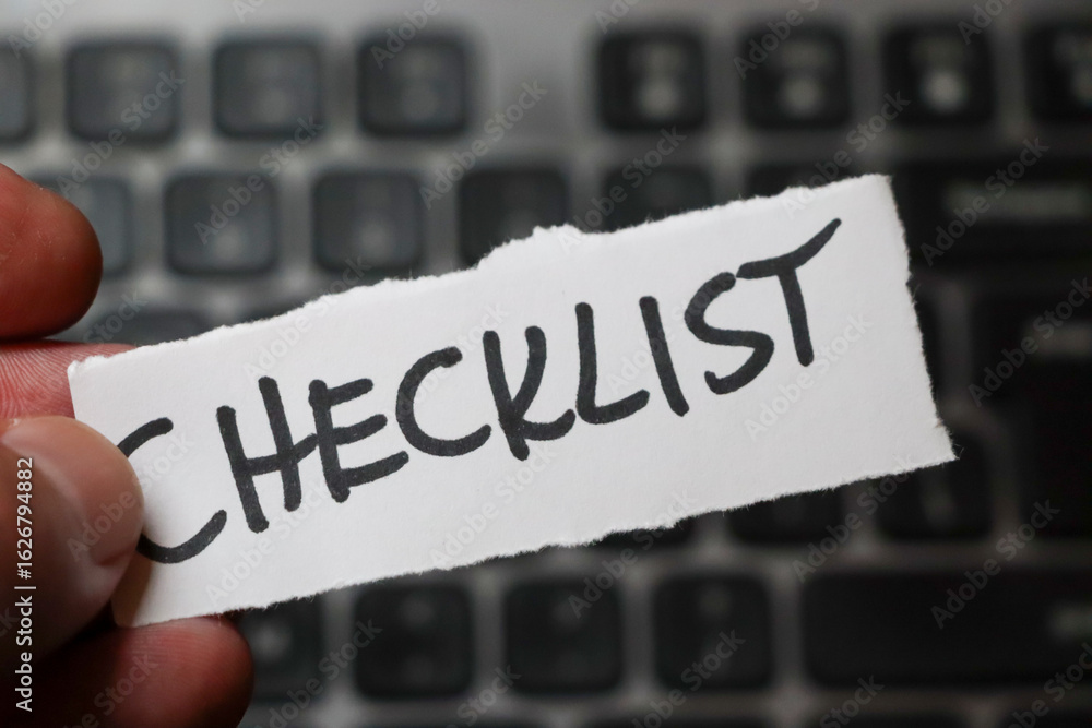 Poster a hand holding a torn paper with the word checklist written in bold, placed on a blurred background 