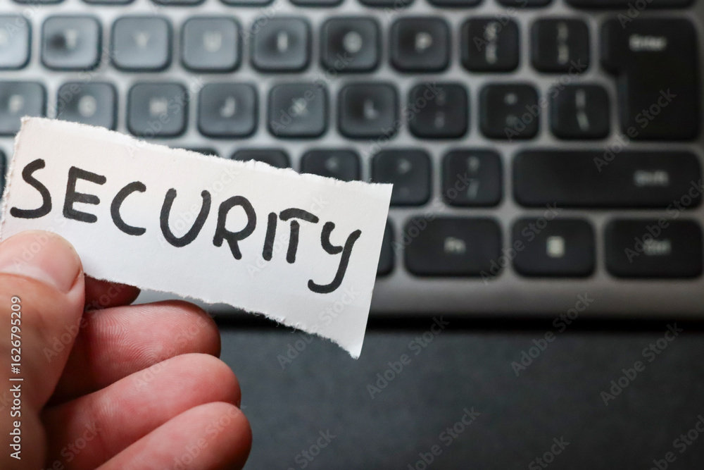 Poster a person holding a torn piece of paper with the word security against a blurred computer keyboard ba
