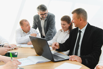 Fototapeta premium Business team analyzing data on laptop during corporate meeting