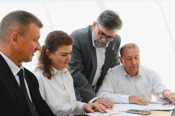 Business team analyzing financial data with senior leader guiding collaboration and decision making...