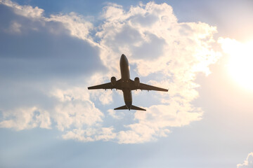 Airplane flying against a backdrop of clouds during sunset in the evening sky