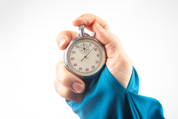 Hand holding a silver stopwatch in a bright setting during a timing event