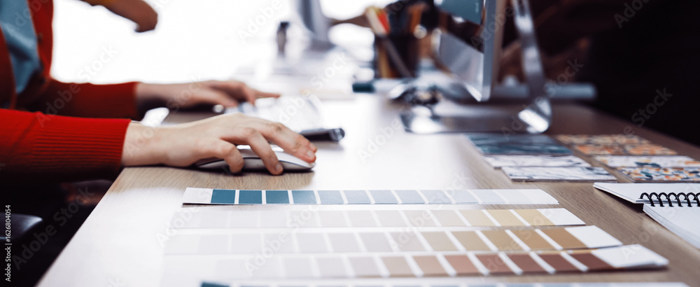 Poster a modern workspace featuring hands engaged in a collaborative design process, showcasing color sampl