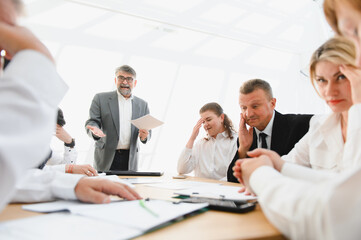 Business team reacting negatively to leader during office meeting
