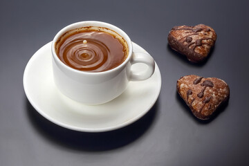 Indulging in hot chocolate paired with heart-shaped cookies on a dark background