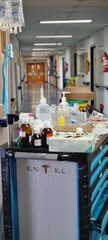 A hospital trolley filled with medical supplies stands in a clinical hallway