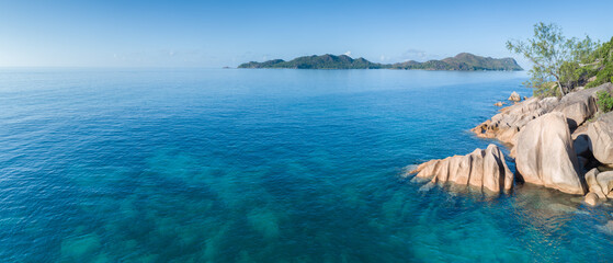 Beautiful blue ocean with a rocky shoreline.  water is calm and clear,  sky is bright blue. scene ipeaceful and serene, with ocean and rocks creating a sense of calm, Vacation concept