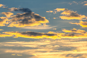Vibrant sunset sky with clouds illuminated in golden hues over the horizon