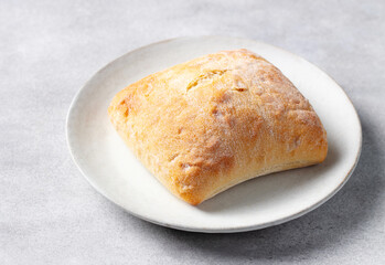 Fresh ciabatta on a white plate. Grey stone background. Close up.