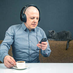 Man enjoys coffee while listening to music and relaxing with a cat in a cozy setting