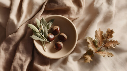 Autumn Arrangement: Acorns, sage, and a decorative leaf on neutral-toned draped fabric. Natural textures.