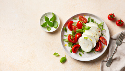 Traditional Italian food. Caprese salad with tomatoes, mozzarella cheese and fresh basil. Beige...