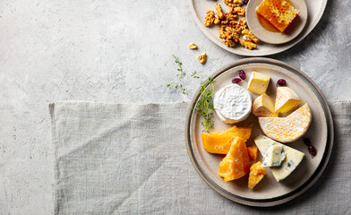 Cheese assortment on a platter. Grey stone and textile background. Copy space. Top view.