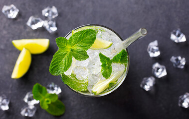 Mojito cocktail with lime and mint, lemonade, ice tea, gin fizz in highball glass. Grey stone background. Close up. Top view.