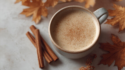 Cozy autumn: Spiced latte with cinnamon sticks and falling leaves, capturing warmth and seasonal comfort.