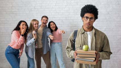 Bullying and racism, problems in college. Sad african american smart guy with glasses holds books...