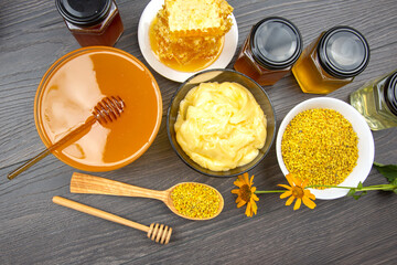 Natural honey, beeswax, and pollen collection with various products on wooden table