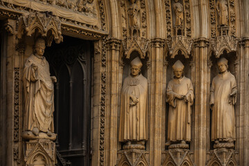 Stone Statues of Saints at the Entrance Door of a Gothic Catholic Church, located in France -...