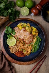 Tom yum egg noodles with bbq pork on wooden background