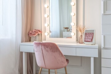 Elegant vanity with Hollywood mirror and pink velvet chair in bedroom