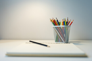  schoolboy workplace: white desk with stand with colored pencils and sketchbook. school supplies on...
