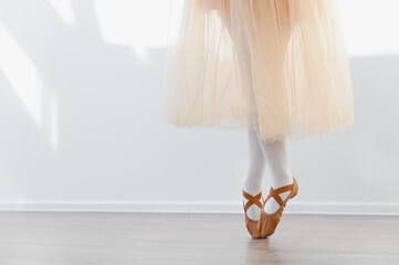 Ballerina girl standing on toes in dance studio, practicing ballet moves