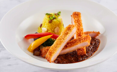 Japanese Katsu Curry with Fried Pork Chop, Yellow Rice, and Vegetables on a White Plate closeup side view of restaurant menus