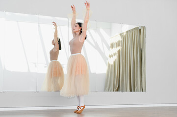 Ballerina practicing ballet in dance studio with mirror and curtains
