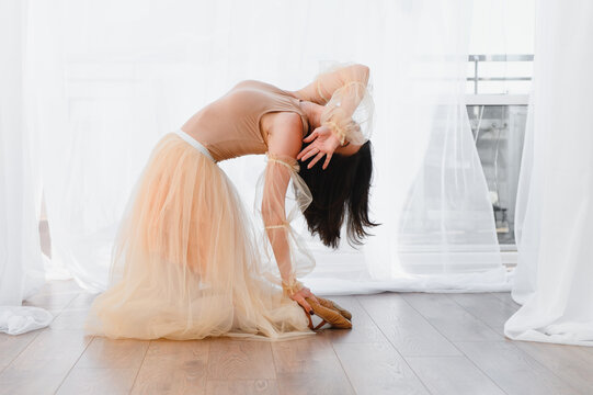 Ballerina kneeling and bending backwards in dance studio