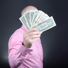 Man displaying cash with a confident expression against a dark background