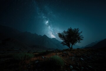 Lone Tree Silhouetted Against Milky Way and Mountain Range in Moody Teal Hues, Ground Level View