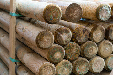 Round logs are stacked in a hardware store as wooden fence posts. These timber blanks are prepared...