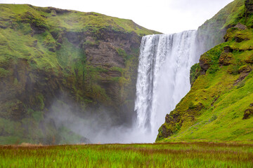 Seljalandsfoss waterfall cascades through Iceland's lush, stunning hills