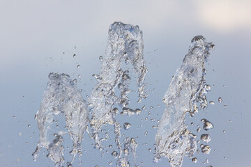 Water splashes into the air from a fountain in a tranquil park during a sunny afternoon