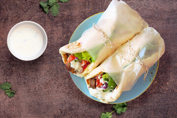 Greek gyros pita wraps with tzatziki. Overhead view on a dark stone background.