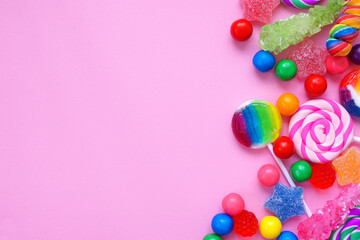 Sweet collection of candies. Overhead view side border over a pink background.