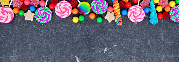 Colorful collection of candies. Above view top border over a black stone banner background.