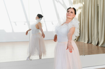 Senior ballerina dancing in a dance studio with mirror practicing ballet
