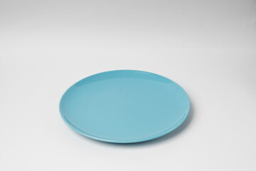 Blue plate, light blue ceramic plate isolated on a white background, shot in a studio with soft lighting