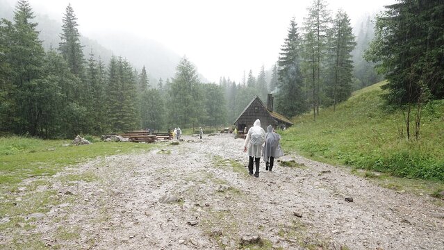 Turyści w pobliżu małej chatki w g&oacute;rach w deszczowy dzień