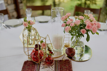 Beautiful table decoration for a romantic dinner with roses, cherries and a golden tray