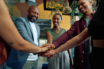 Diverse group of business people stacking hands for teamwork in office