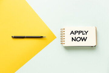Apply now. Conceptual words, corporate phrases, a yellow arrow, and a black pen point to a notebook...
