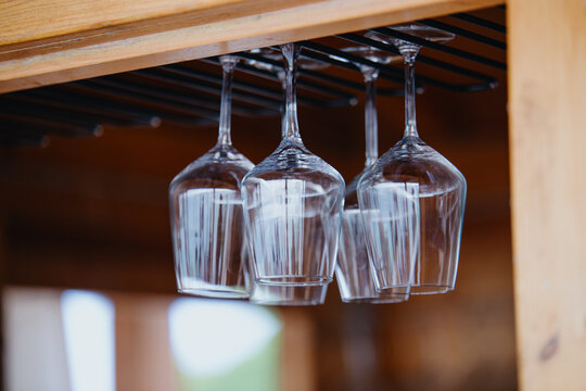 Glasses hanging upside down above the bar counter. Clean transparent glasses - Powered by Adobe