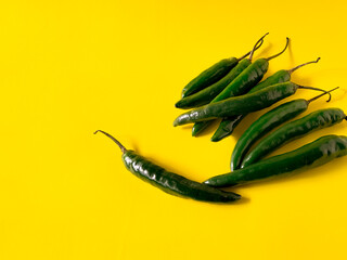 Green chili peppers are scattered on a bright yellow background.