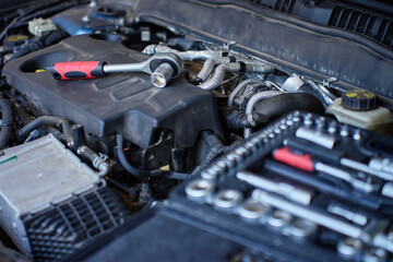 Close-up of wrench socket tool lying on car engine during maintenance work. Vehicle repair concept