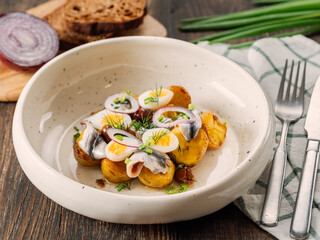 Anchovy or sprat or sardine with potatoes in restaurant-style plating, served onion and greenery....