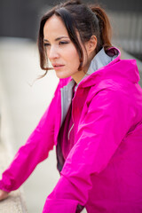 Focused woman in bright pink windbreaker leaning forward outdoors